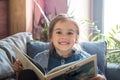 Little girl is reading a book in the living room on the couch Royalty Free Stock Photo