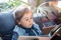 Little girl is reading a book in the living room on the couch Royalty Free Stock Photo