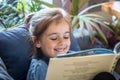 Little girl is reading a book in the living room on the couch Royalty Free Stock Photo