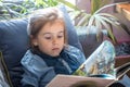 Little girl is reading a book in the living room on the couch Royalty Free Stock Photo