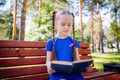 Little girl reading a book outdoors. Royalty Free Stock Photo