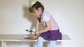 Little girl reading book while sitting at table with loupe