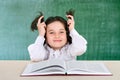 Little girl reading a book smiling teenager near a school board Royalty Free Stock Photo