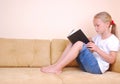 Little girl reading book on sofa Royalty Free Stock Photo