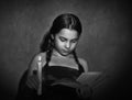 Little girl reading book and studying in candle light in dark room Royalty Free Stock Photo