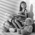 Little girl is reading a book to a teddy bear. Royalty Free Stock Photo