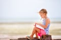 Little adorable girl reading book during tropical white beach Royalty Free Stock Photo