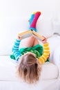 Little girl reading a book on a white couch