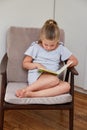 Little girl reading sitting in chair