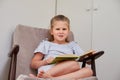 Little girl reading sitting in chair