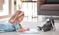 Little girl reading storybook at home with teddybear. Adorable caucasian girl lying on floor and reading a story to her