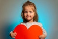 Little girl with red big blank heart looking in camera