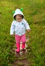 Little girl in red boots walks along path with rain puddles Royalty Free Stock Photo