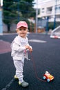 Little girl in a red cap stands on the sports ground with a toy car Royalty Free Stock Photo