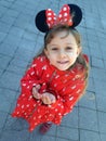 The little girl in a red coat with ears of Minnie Mause on the head Royalty Free Stock Photo