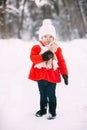 Little girl in red coat with a teddy bear having fun on winter day. girl playing in the snow Royalty Free Stock Photo