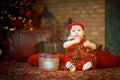 little girl in red dress against background of Christmas tree holds Christmas garland in her hands. baby 6 month old celebrates