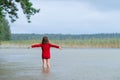 Little girl in a red dress dancing in the rain