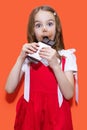 A little girl in a red dress holds a bar of chocolate in her hands with a surprised expression Royalty Free Stock Photo