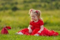 little girl in a red dress sitting on the lawn Royalty Free Stock Photo