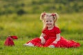 little girl in a red dress sitting on the lawn Royalty Free Stock Photo