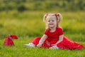 little girl in a red dress sitting on the lawn Royalty Free Stock Photo