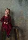 Little girl in red dress sitting on wooden stair and smiling Royalty Free Stock Photo