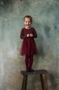 Little girl in red dress standing on wooden chair and smiling Royalty Free Stock Photo