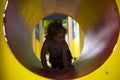 Little girl with red hair crawling through a tunnel in the playground Royalty Free Stock Photo