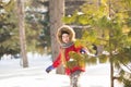 Little girl in red jacket walks gladly in snow in wood