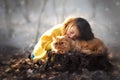 Little girl with red persian cat in the forest. Soft natural light. Cat is looking forward. Girl lay down her cheek on cat