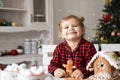 little girl in red pyjama holding decorated Christmas gingerbread men cookie