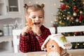 little girl in red pyjama holding decorated Christmas gingerbread men cookie