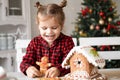 little girl in red pyjama holding decorated Christmas gingerbread men cookie