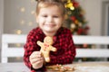 little girl in red pyjama holding decorated Christmas gingerbread men cookie. selective focus