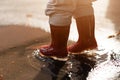 Little girl in red rainboots playing in puddle after rain. Happy fall childhood activity