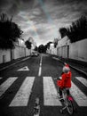 Little girl with red riding hood pointing rainbow from the street in black and white selective color Royalty Free Stock Photo