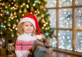 Little girl in red santa hat holding christmas gift box Royalty Free Stock Photo