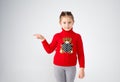 a little girl in a red sweater stands on a white isolated background pointing her finger to the side. place for text Royalty Free Stock Photo