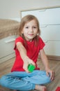 A little girl in a red T-shirt in the children`s room plays with colorful cubes. Holds the cube to the camera. Vertical photo Royalty Free Stock Photo