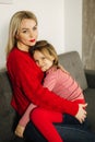 Little girl in red tights with mom in red sweater. Happy family at home. Daughter hug her mother Royalty Free Stock Photo