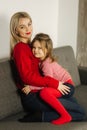 Little girl in red tights with mom in red sweater. Happy family at home. Daughter hug her mother Royalty Free Stock Photo