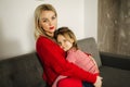 Little girl in red tights with mom in red sweater. Happy family at home. Daughter hug her mother Royalty Free Stock Photo