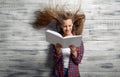 Little girl reding a book against powerful airflow