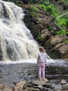 Little girl relaxing and enjoying beautiful view on vacation hiking trip at waterfall. Travelling with kids concept