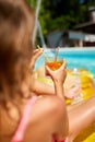 Little girl relaxing in swimming pool, enjoying suntans, drink a juice on inflatable yellow mattress Royalty Free Stock Photo