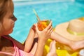 Little girl relaxing in swimming pool, enjoying suntans, drink a juice on inflatable yellow mattress Royalty Free Stock Photo