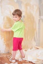 Little girl remove old wallpapers from wall