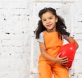 Little girl in repairman uniform with helmet in hands