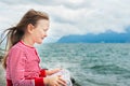 Little girl resting by the lake on a very windy day Royalty Free Stock Photo